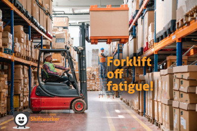Shiftworker warehouse worker driving a factory tow tractor and moving pallets in a warehouse
